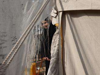 A Palestinian woman seen through the folds of a makeshift tent in the Rafah area, southern Gaza.