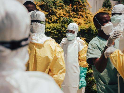 Colleagues help one another into their personal protective equipment (PPE) before decontaminating homes in Bunia, Ituri province, DR Congo.
