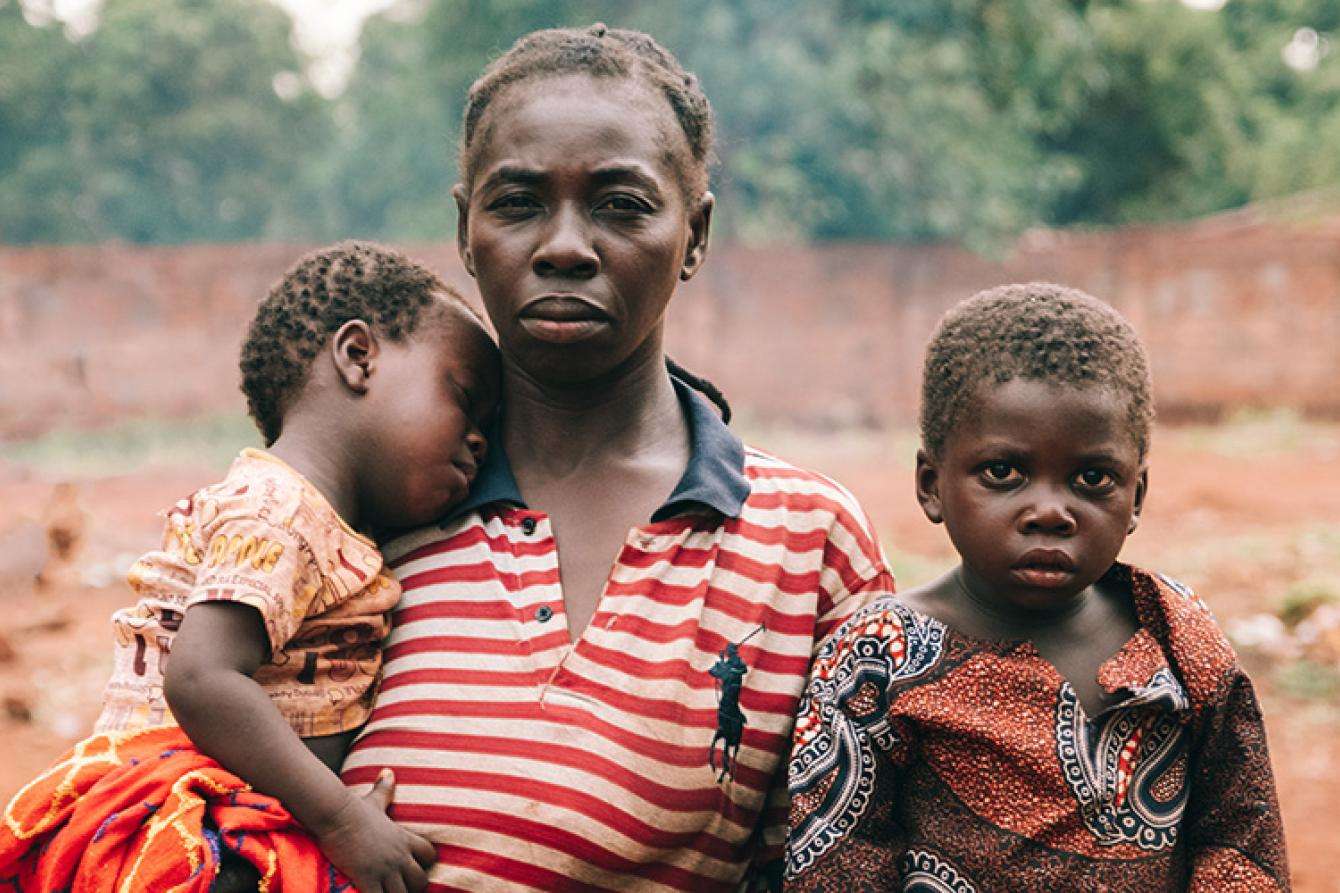 A woman in striped shirt with two young children in Central African Republic