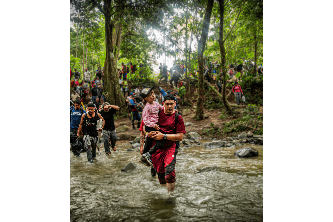 A boy carries a young child across a river in the Darién Gap, Panama.