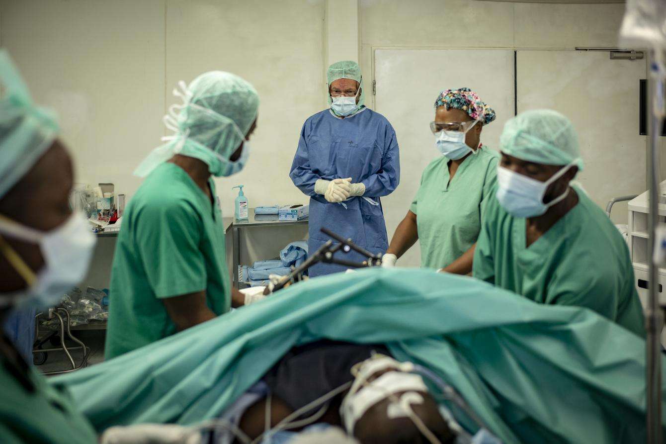 A surgical team prepares to operate on a patient with a leg injury.