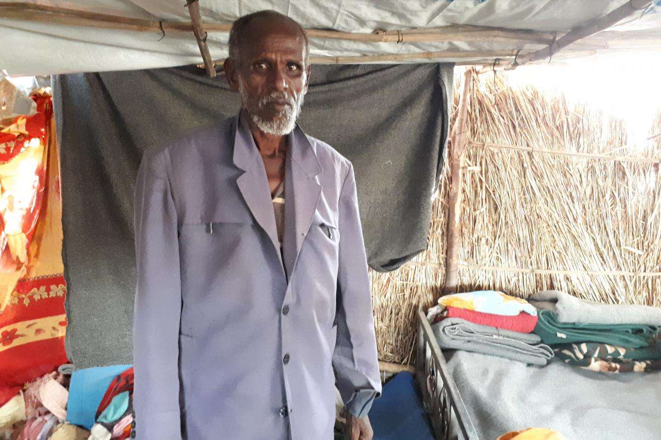 An elderly man standing in a shelter