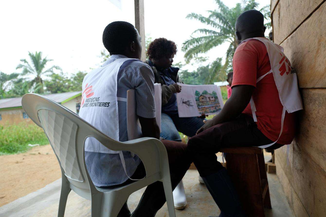 MSF community outreach specialist Wivine Bokotogi shows a set of flashcards on malaria prevention and treatment to two local health promoters in Metale, North Kivu province, Democratic Republic of Congo.