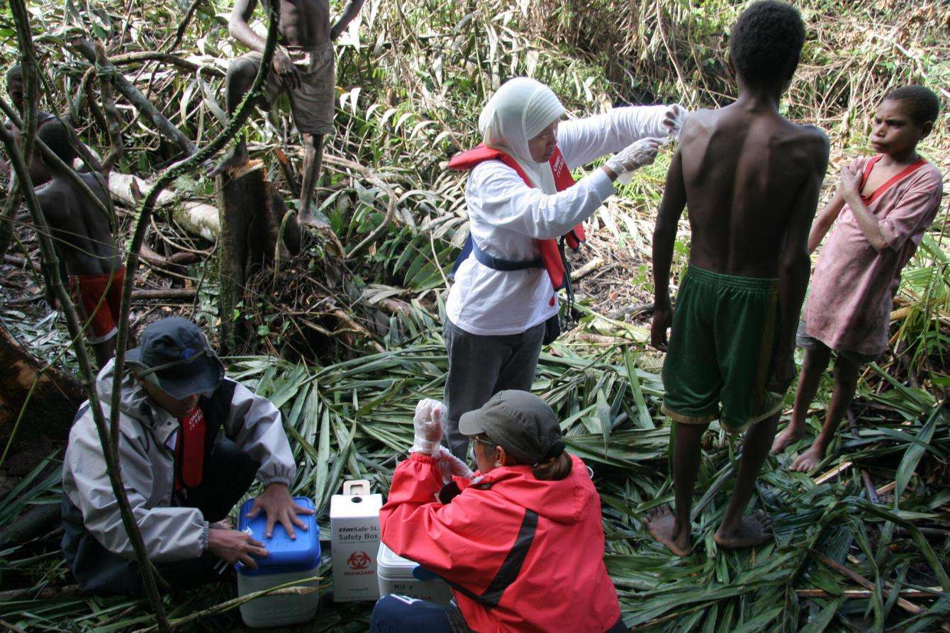Women vaccinating men in a dense forest in Indonesia.