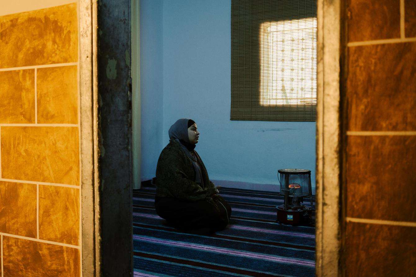 Woman prays in a small dark room