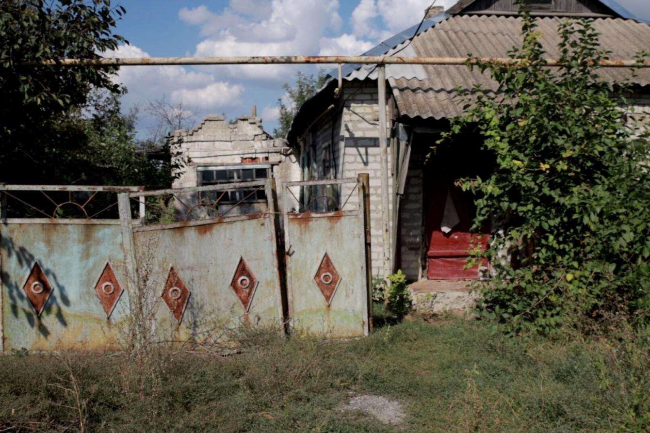 A dilapidated house with tin roof and broken gate