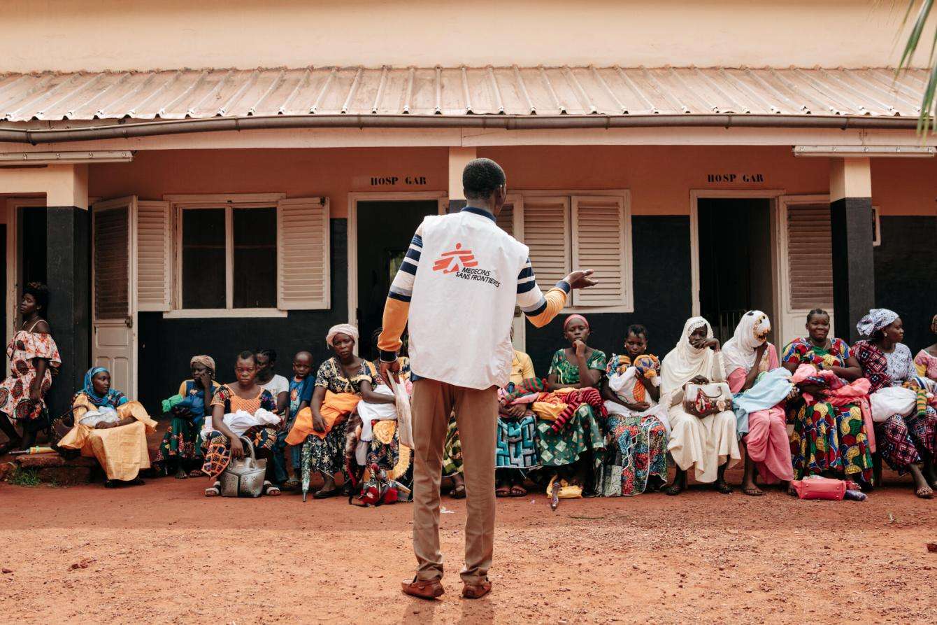 An MSF health care worker in white vest stands in front of a group of patients at Bangassou hospital in Central African Republic.