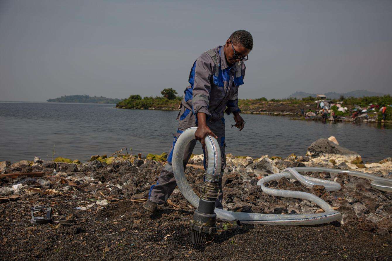 An MSF water and sanitation worker installs pipes in ground beside Lake Kivu in Democratic Republic of Congo
