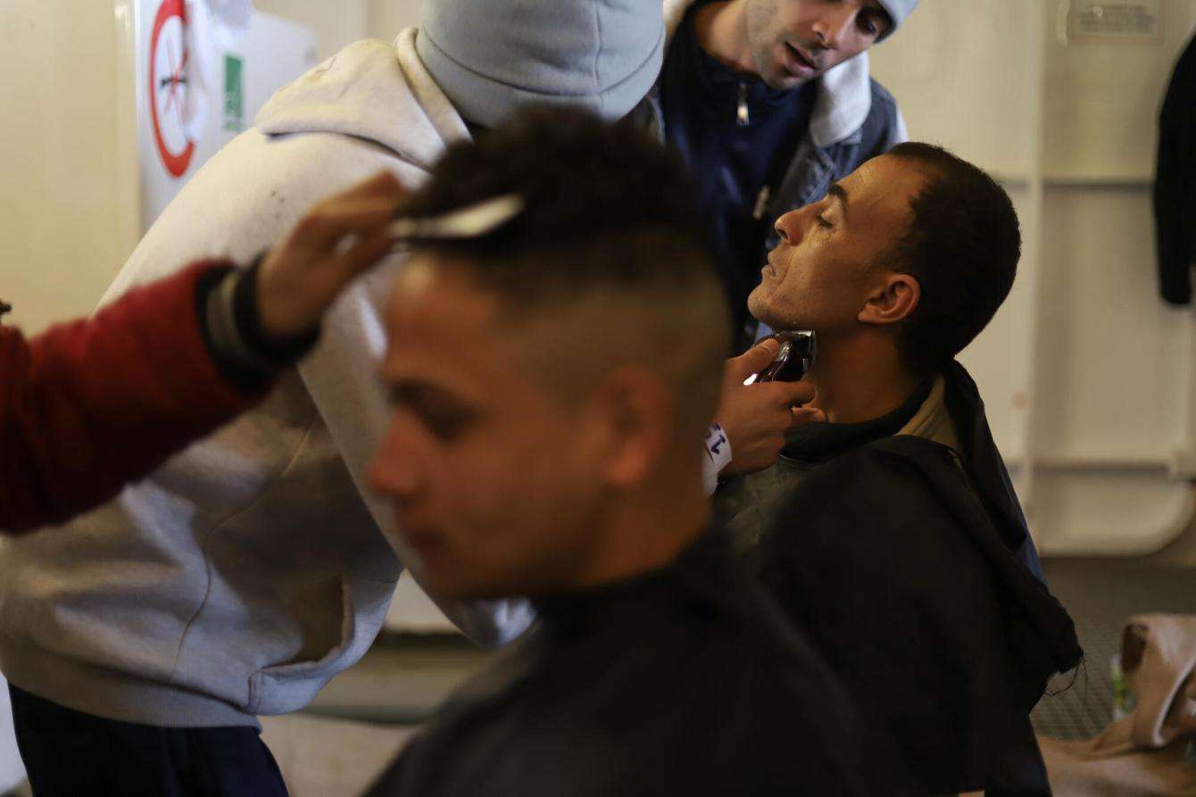 Two men are getting their hair cut and their face shaved on MSF's Geo Barents search and rescue ship on the Mediterranean.