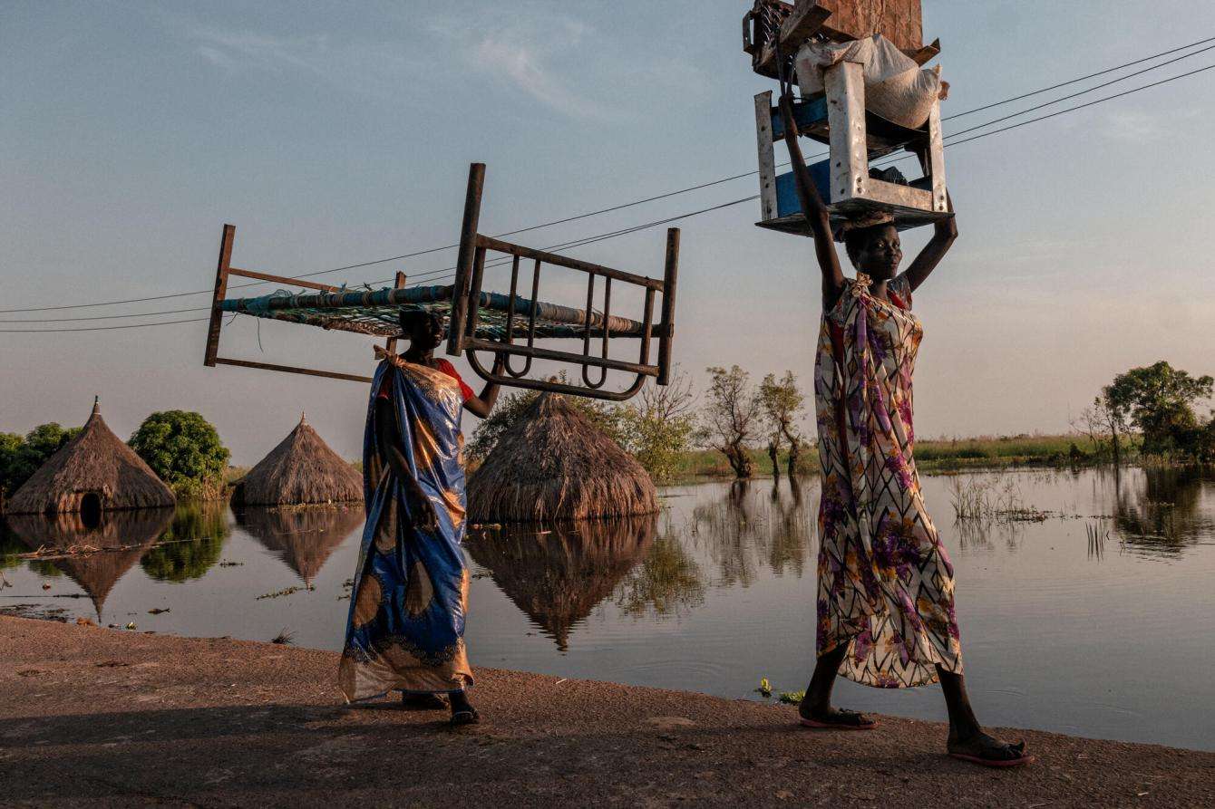 Women carry objects on their heads during floods in South Sudan.