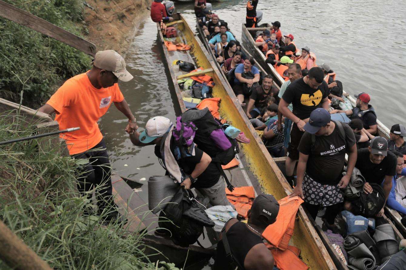 People disembark from canoes in a river in the Darién Gap between Panama and Colombia, along the Central American migration route.