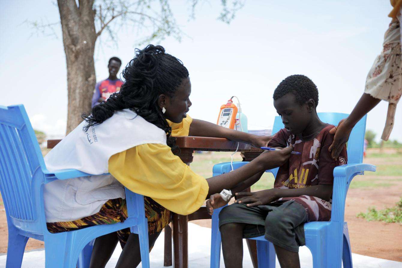 MSF nurse, Rejoice Albino examines Osman Mahmod, a child at Wedweil refugee camp in South Sudan.