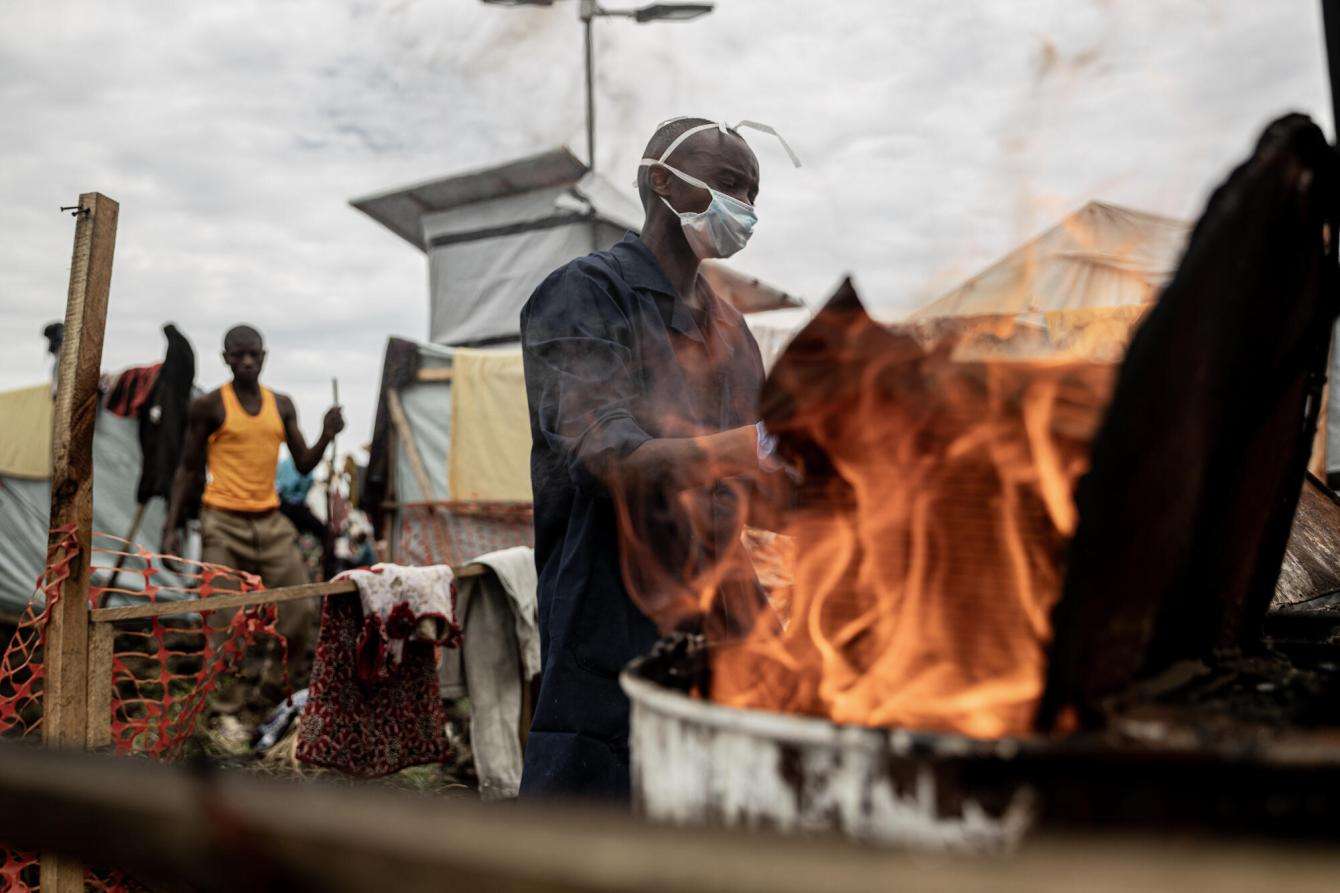 A displaced man in Democratic Republic of Congo makes a fire in a camp for displaced people