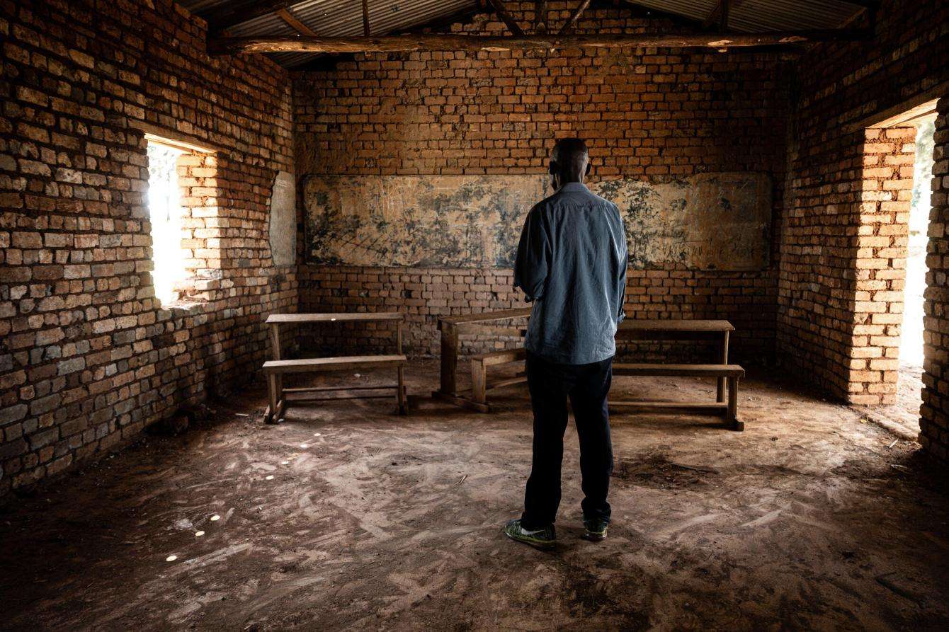 A man stands facing away in an empty room in Democratic Republic of Congo.