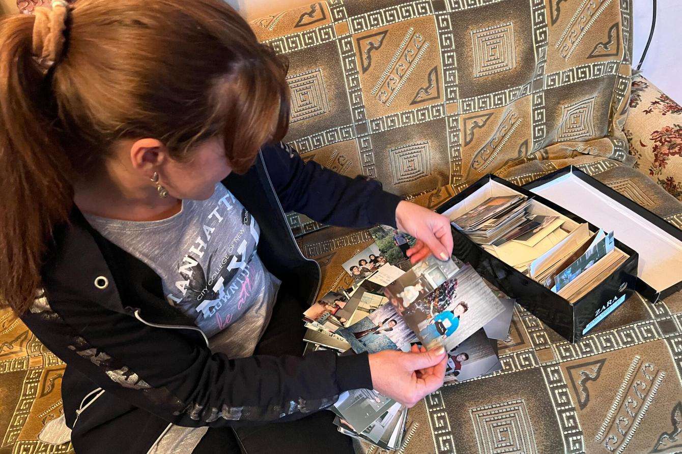 A displaced woman looks at photos in an album she took while fleeing Nagorno-Karabakh.