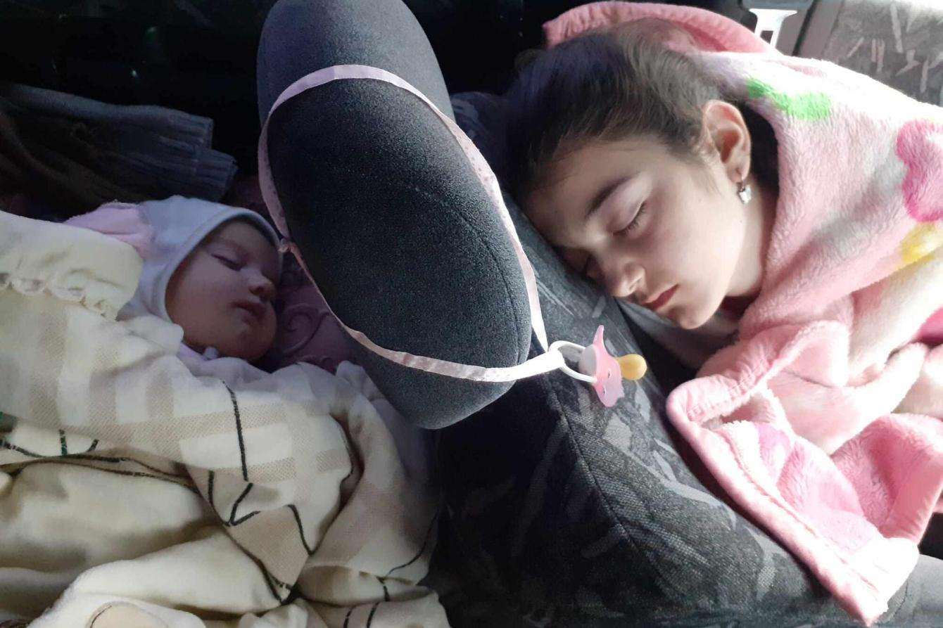A baby and child sleep in a car while fleeing Nagorno-Karabakh.