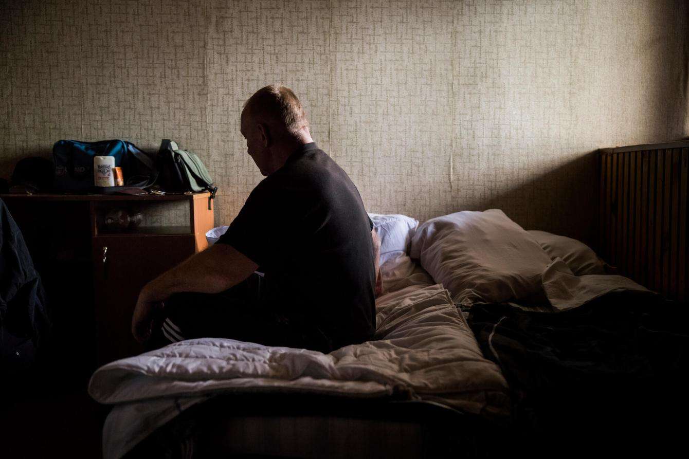A Ukrainian man and MSF mental health patient sits on a bed.