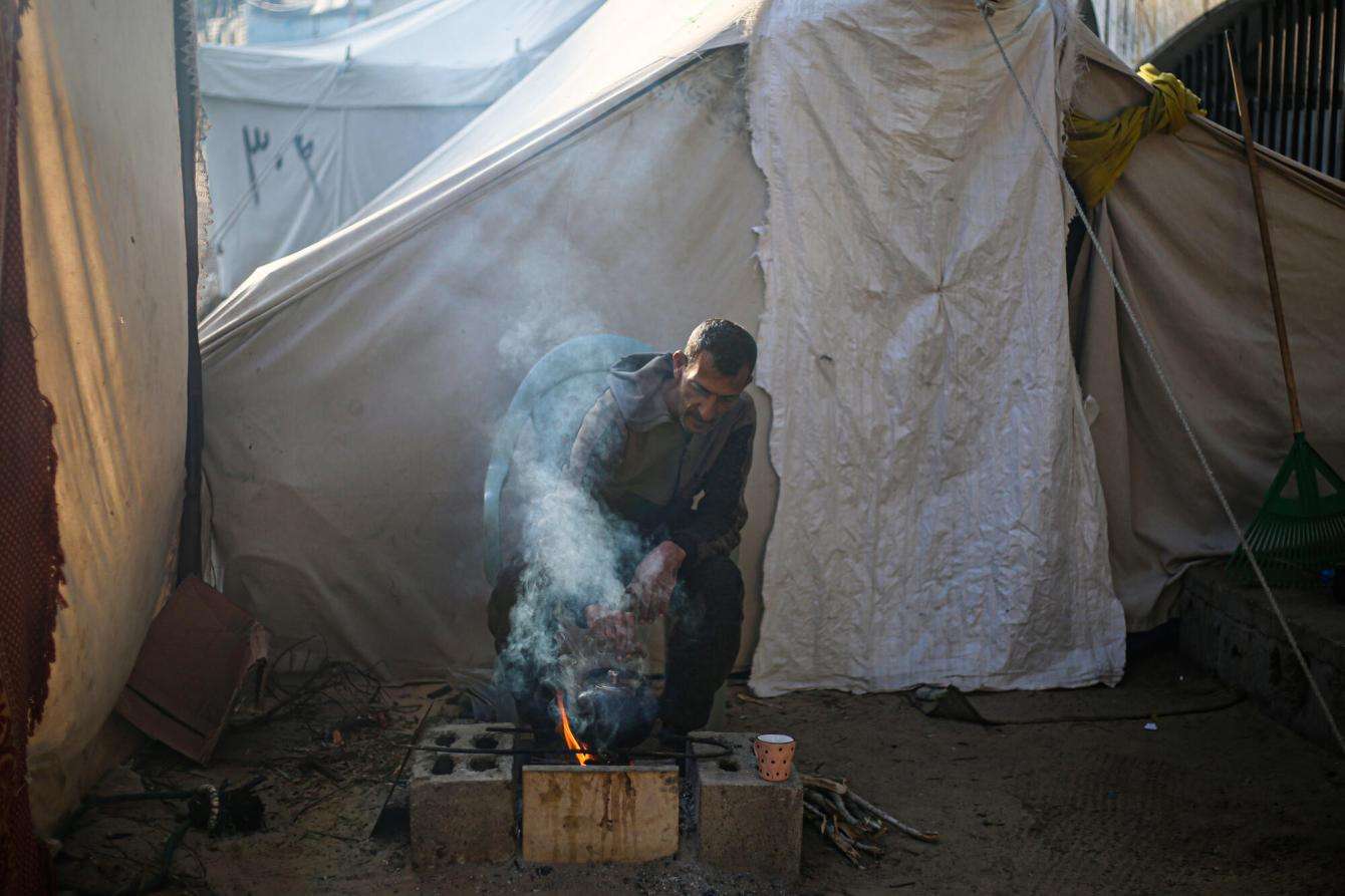 A Palestinian man lights a fire in his tent in Rafah, southern Gaza.