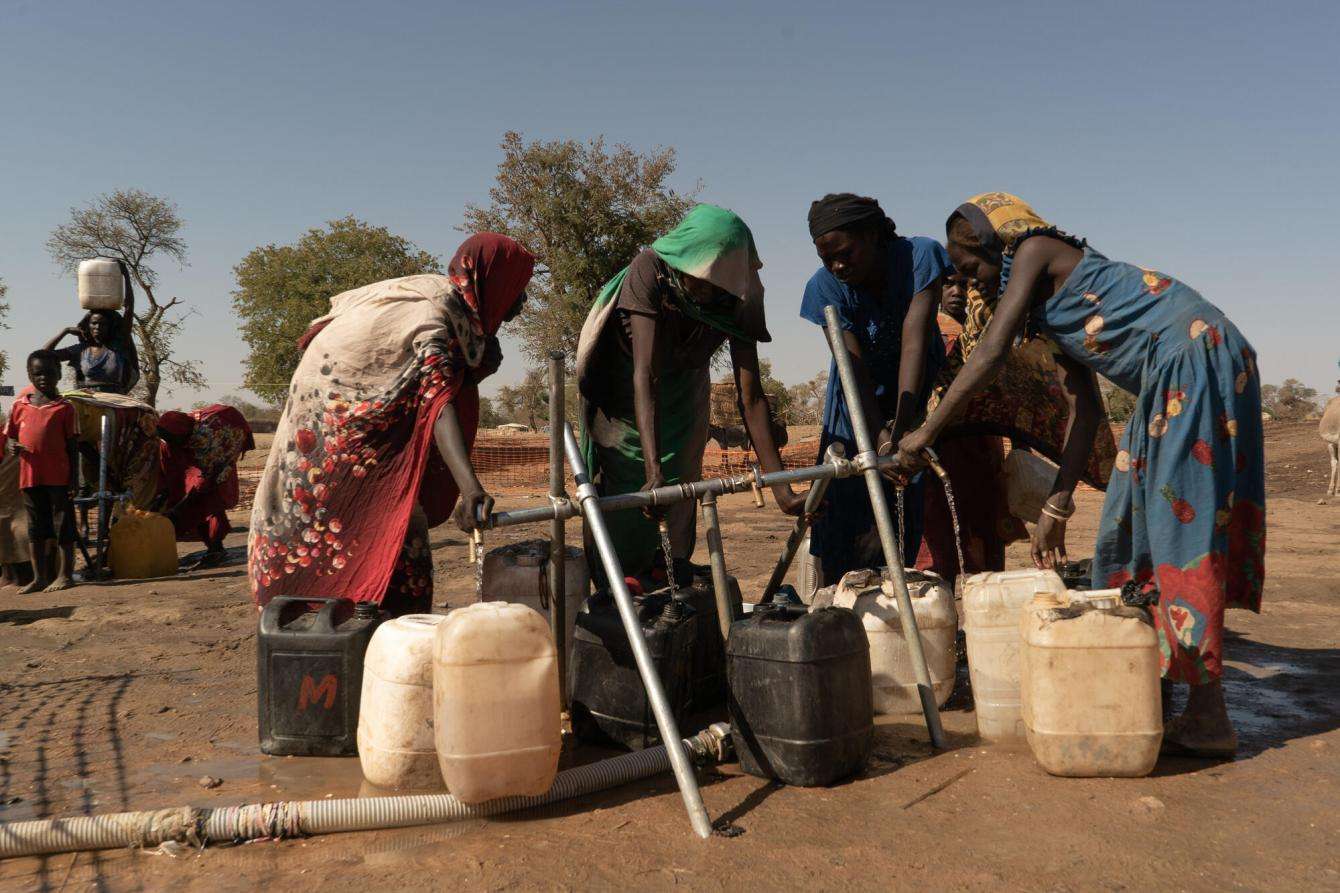 Women fill drinking water containers in Daguessa camp.