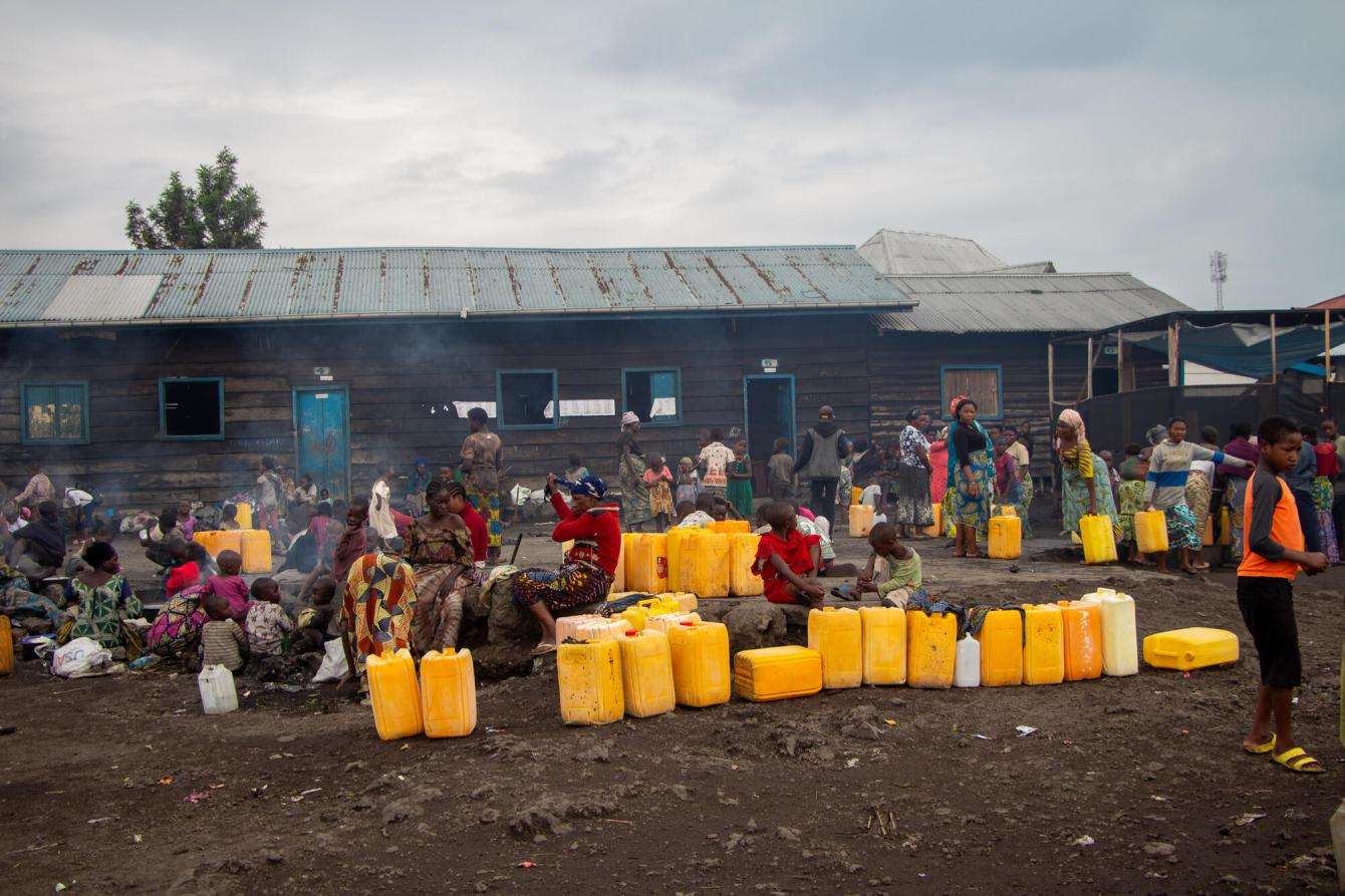 Displaced people line up to fill up jugs of water in DR Congo.