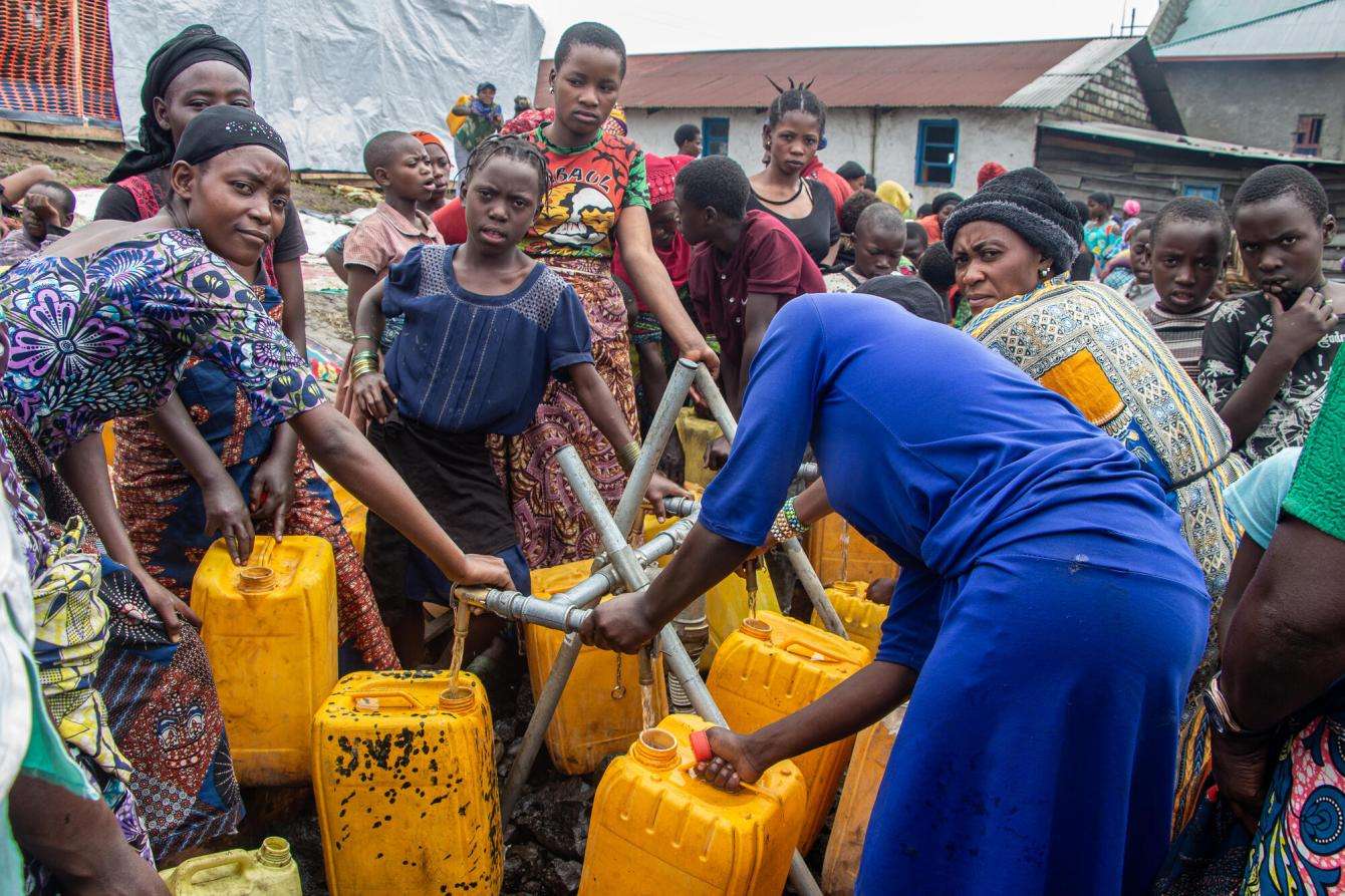 Displaced women fill jugs of water in a camp in eastern DR Congo.