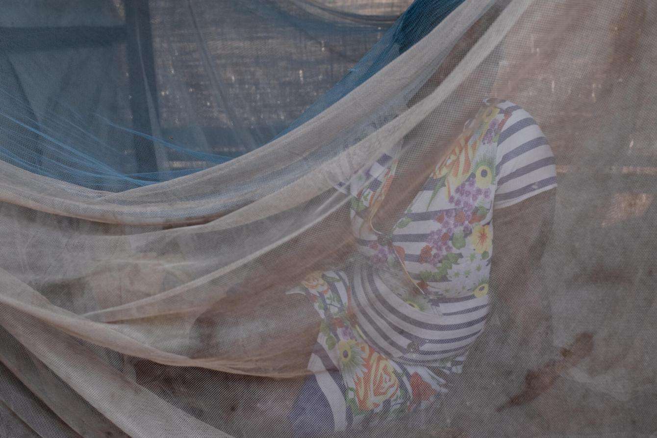 A survivor of sexual violence sits behind a mosquito net in her tent in Mbawa camp for displaced people in Nigeria.
