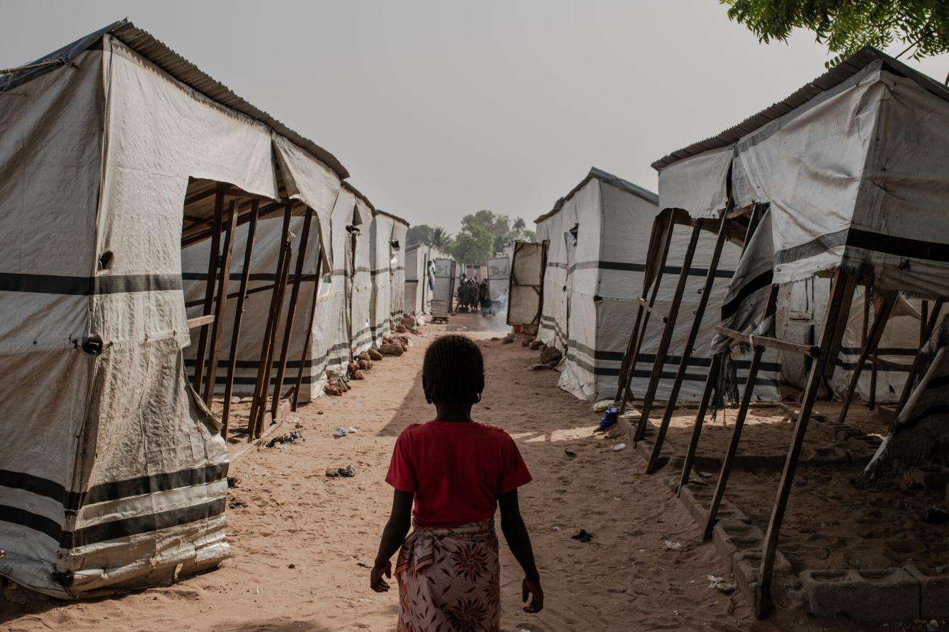 A young woman looks down an alley between tents in a displacement camp in Nigeria.