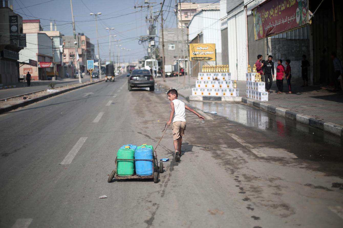 Boy pulling cart with jugs of water in Khan Younis, Gaza.
