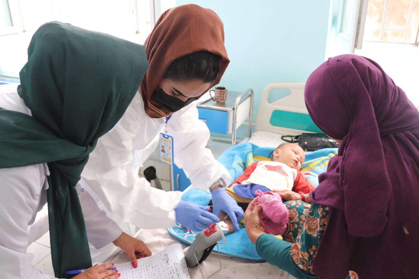 Three nurses care for a child with measles in Afghanistan. 