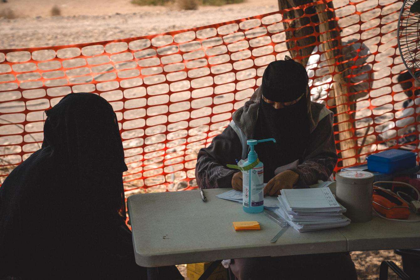 A woman speaks with a health care worker in Yemen. 