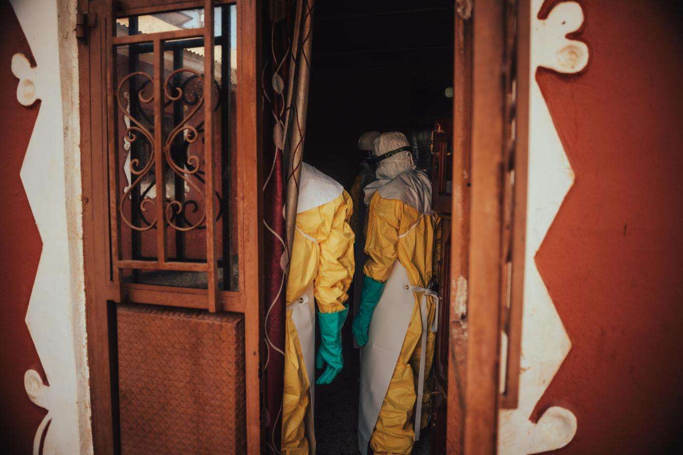 A team of hygiene specialists begin decontaminating a home, spraying a chlorine-based solution that kills the virus on furniture, curtains, mattresses, clothing — anything that has come into contact with an infected patient.
