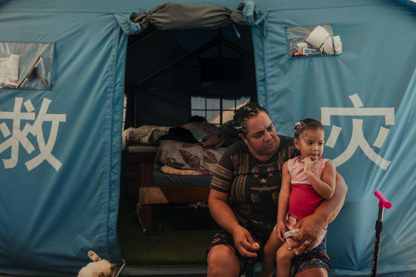 A displaced woman and child in front of a tent in Venezuela.