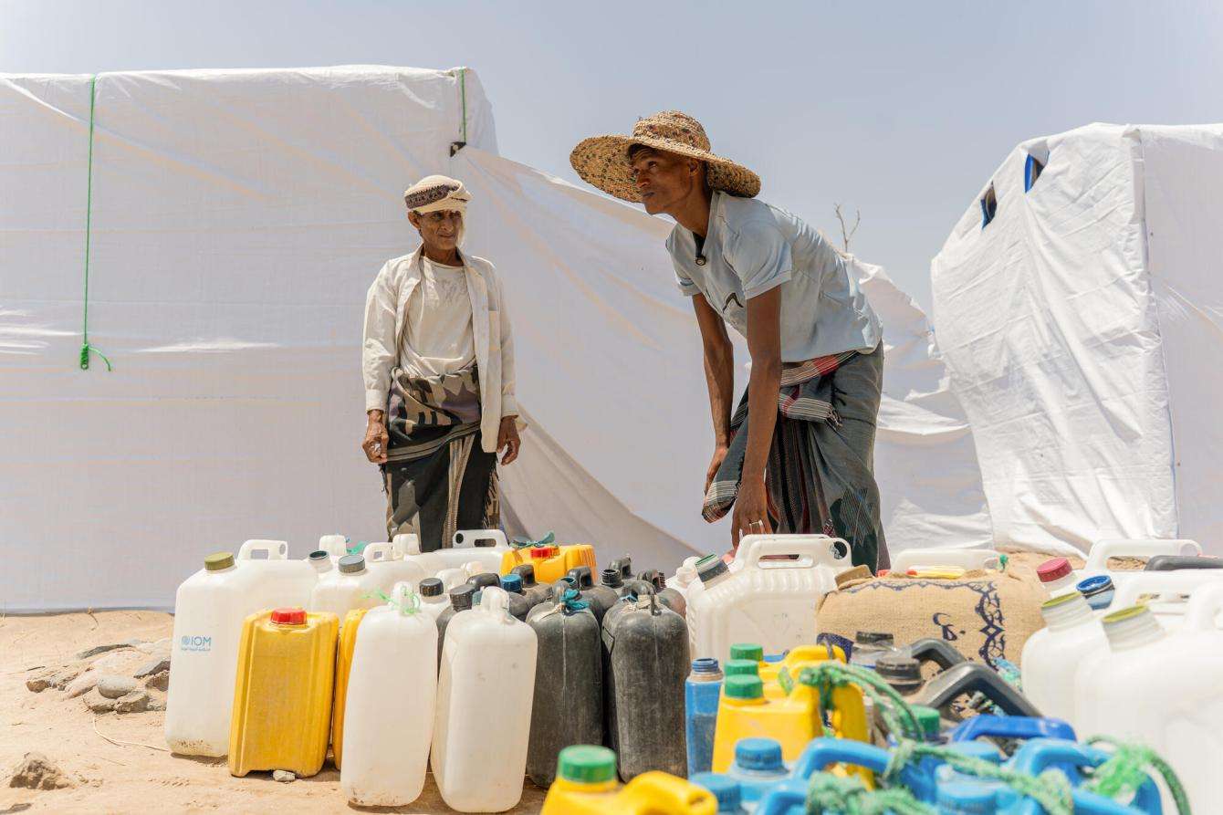 Displaced people fill jerrycans of water in a camp in Yemen.