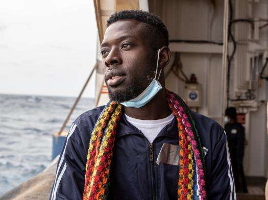 Young man looks over deck of rescue ship at sea