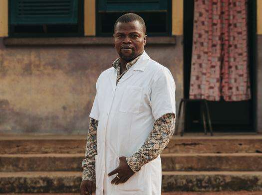 Dr. Louis-Marie Sabio in a white lab coat standing in front of an MSF health facility in Central African Republic.