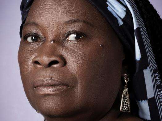 A woman in head wrap against purple background.