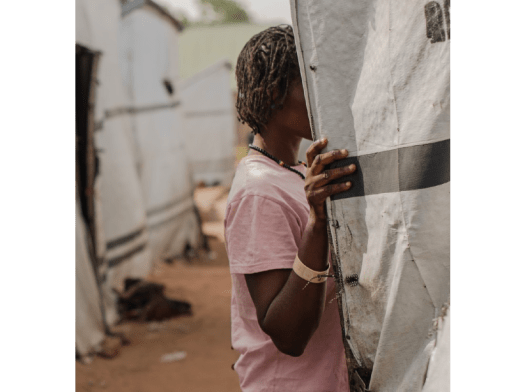 Seember speaks with a neighbor inside their tent in a camp in Nigeria.