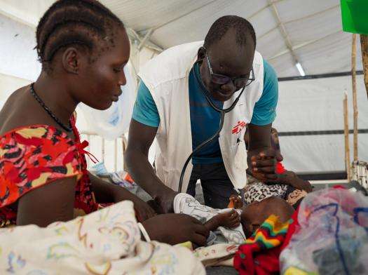 MSF doctor in white vest examines a child for measles as the mother watches in an MSF facility in Leer, Unity state, South Sudan. in  