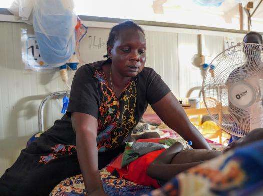 A mother looks at her niece lying receiving pediatric care for measles from MSF in Bentiu, Unity state, South Sudan. 