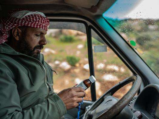A Palestinian Bedouin man looks at a prescription medicine bottle from MSF in his car in the West Bank, Occupied Palestinian Territories.