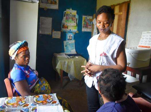 MSF staff in white vest assists maternal health patients in Sierra Leone