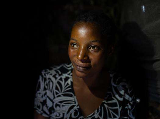 A woman who is a sexual violence survivor in Democratic Republic of Congo against a black background.