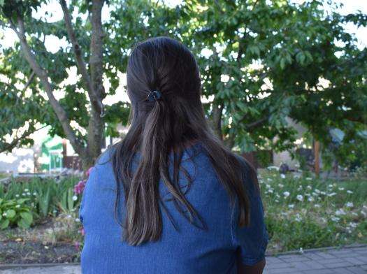 An MSF patient with long brown hair looks into a wooded area in Belgorod.