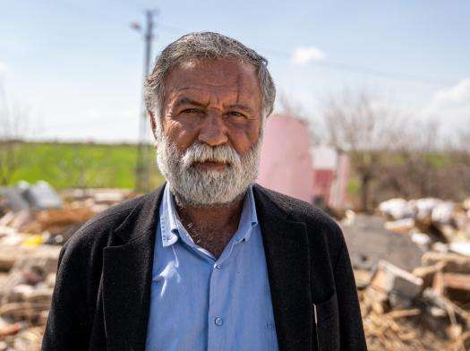 An older man standing on the rubble that is left of his home after it was destroyed in the earthquakes in Turkey.