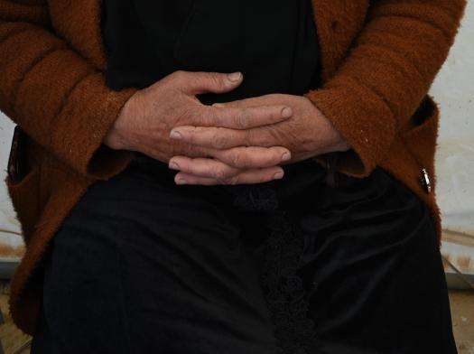 A woman's hands folded in her lap in the West Bank, Palestine. 