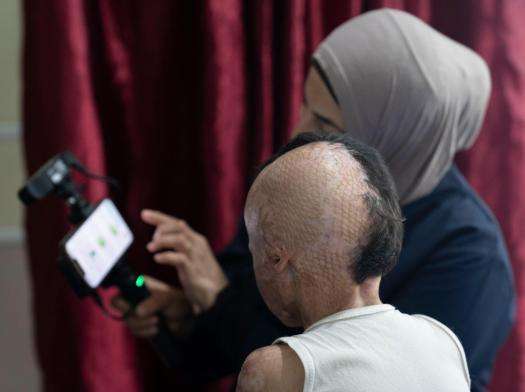 Ibtihal explains how the 3D scanner works to Joud so he can feel at ease during the scan.