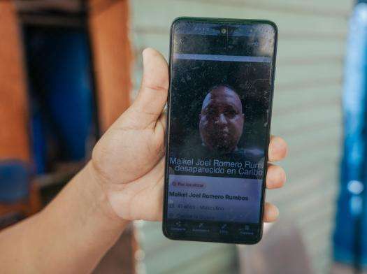 Yusmari Romero, 46, holds a picture of her missing brother, Maikel Romero, outside her makeshift shelter in a public school in Playa Grande, Venezuela.