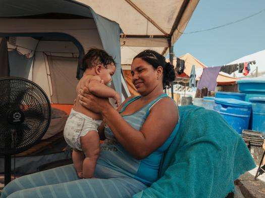 Greydiel Álvarez, 22, holds her son Kleiber Capote, 3 months, after bathing him. The family lives in a temporary encampment set up outside Mare Abajo housing complex, that partially collapsed during the twin earthquakes in Venezuela.