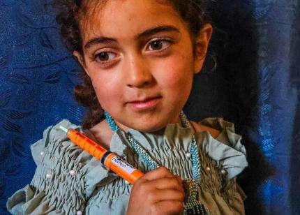 A young girl holds her insulin pen for diabetes in Lebanon.