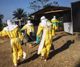 MSF staff transport a person who may have Ebola from an ambulance that broke down before reaching the MSF Ebola management center in Kailahun, a three-hour drive from the patient’s home. 